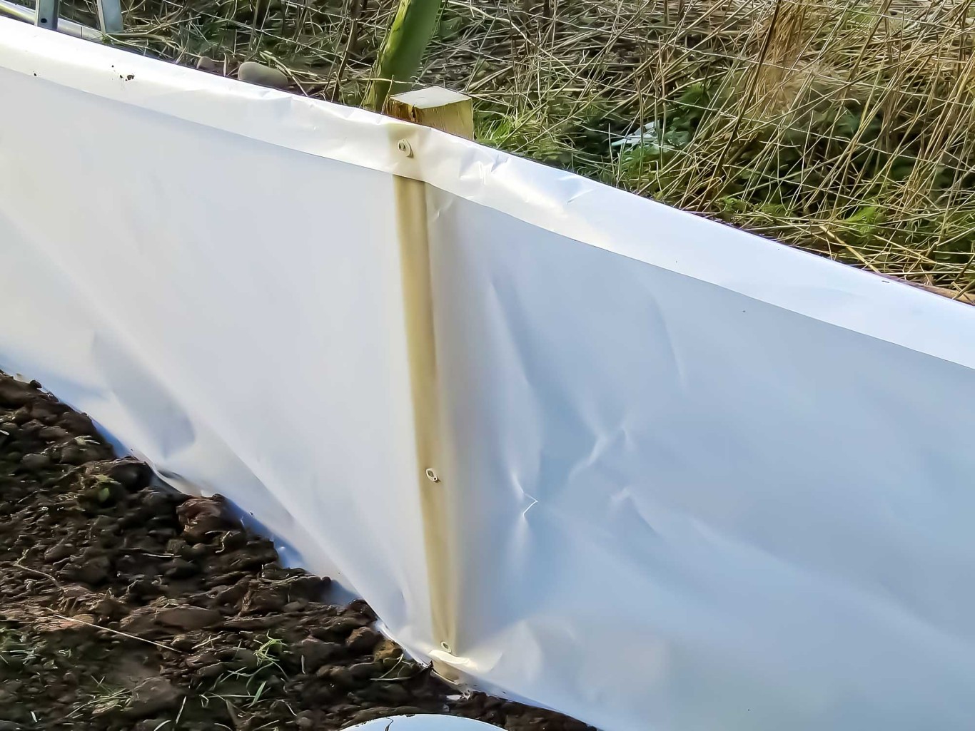 Close up of white reptile fencing with wooden posts.