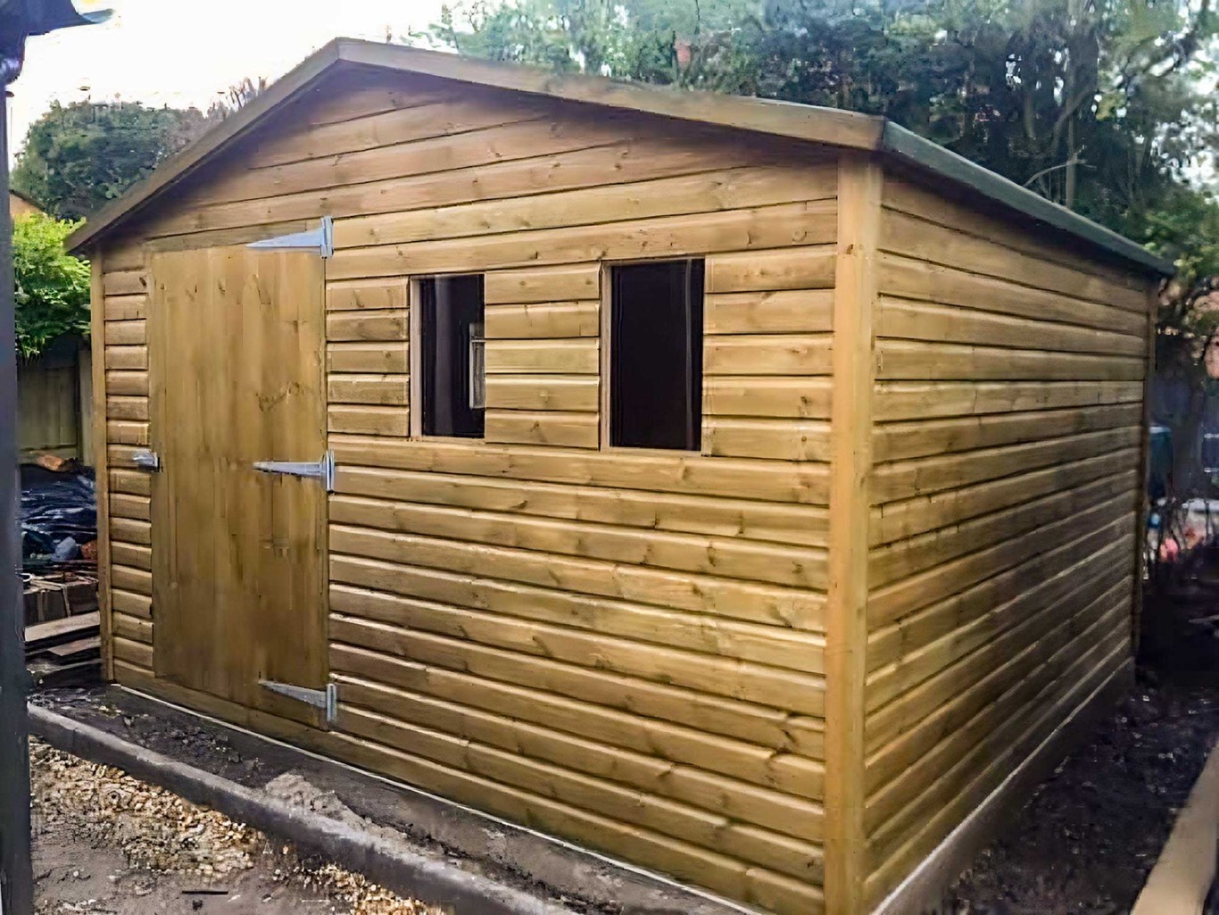 Large workshop shed in garden with two front windows.