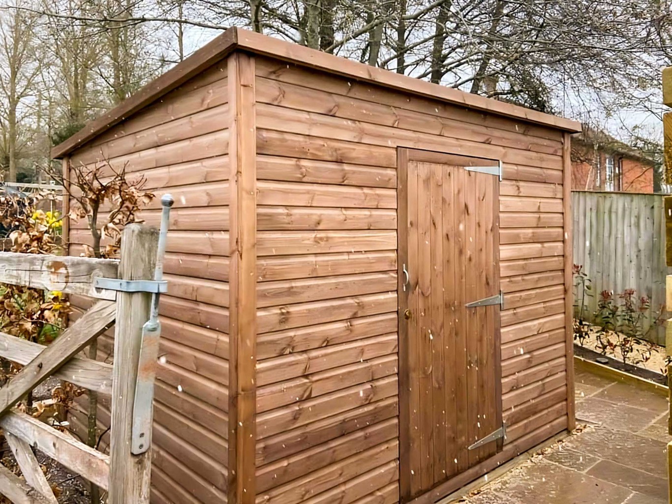 Large pent roof shed in a garden with a single door.