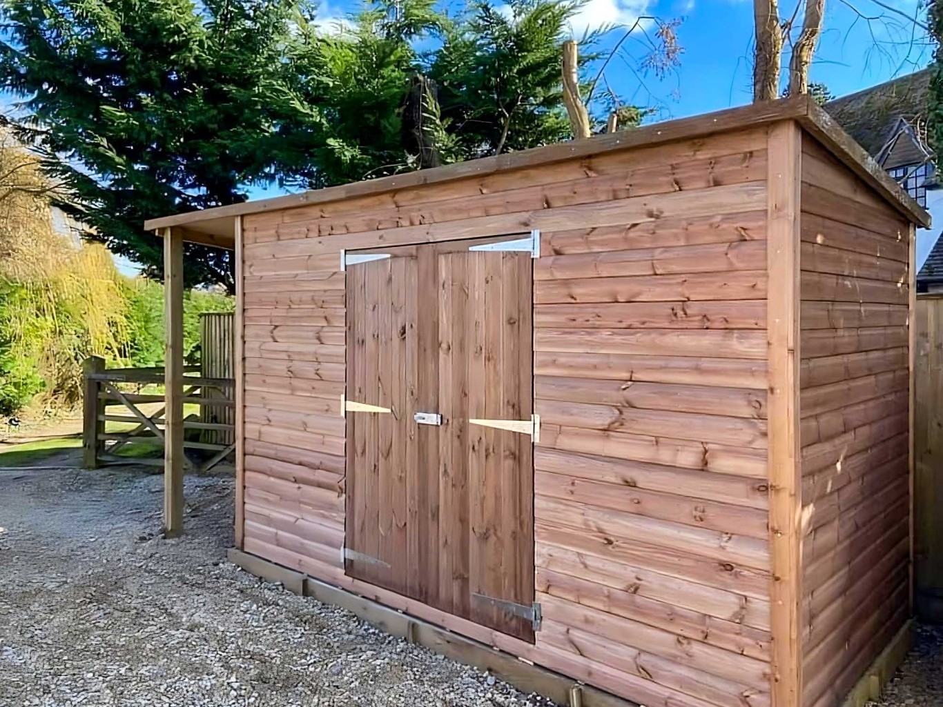 Large timber shed with double doors and shelter on the side.