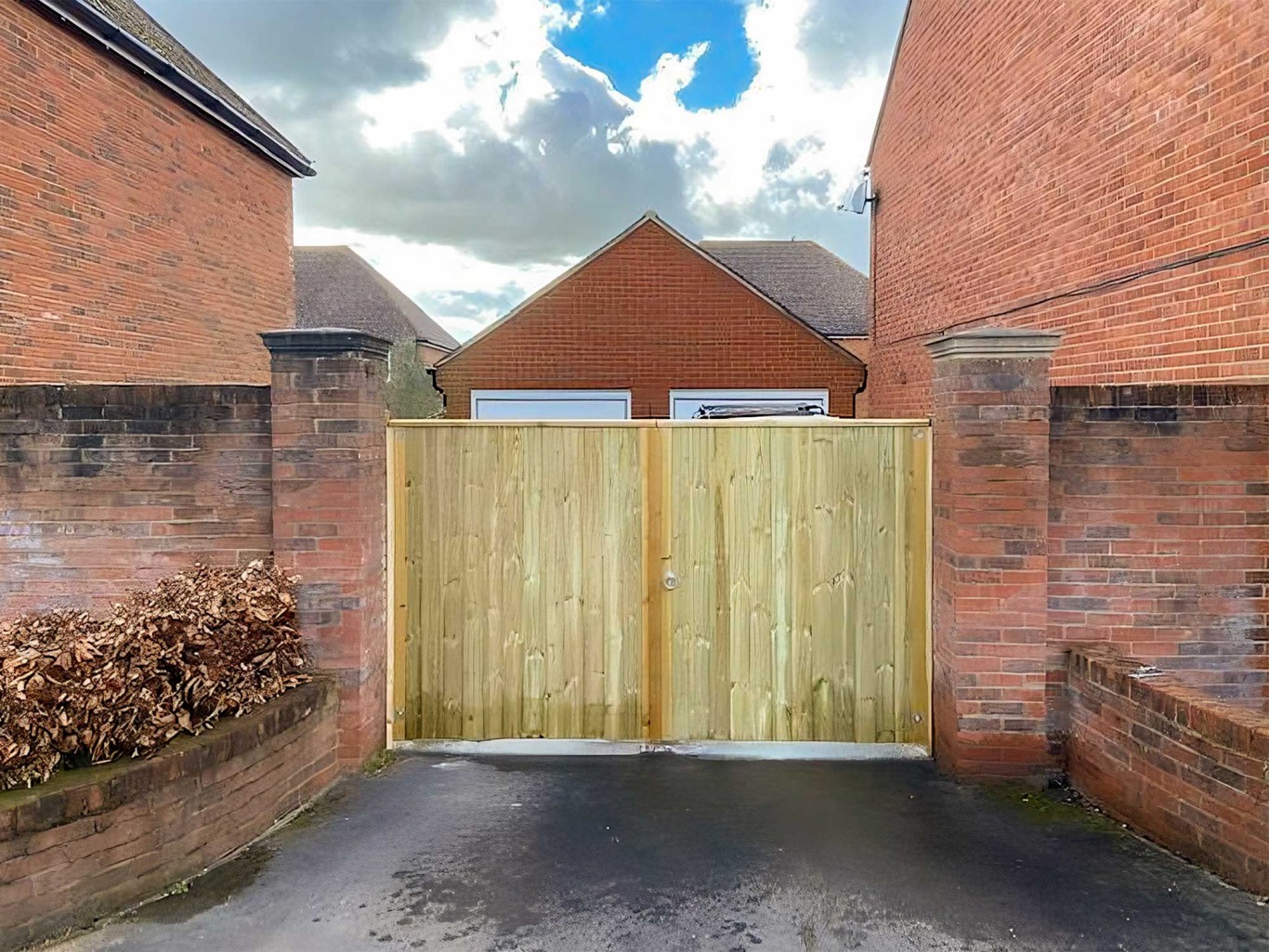 Large tongue and groove entrance gate in wood with brick walls either side.
