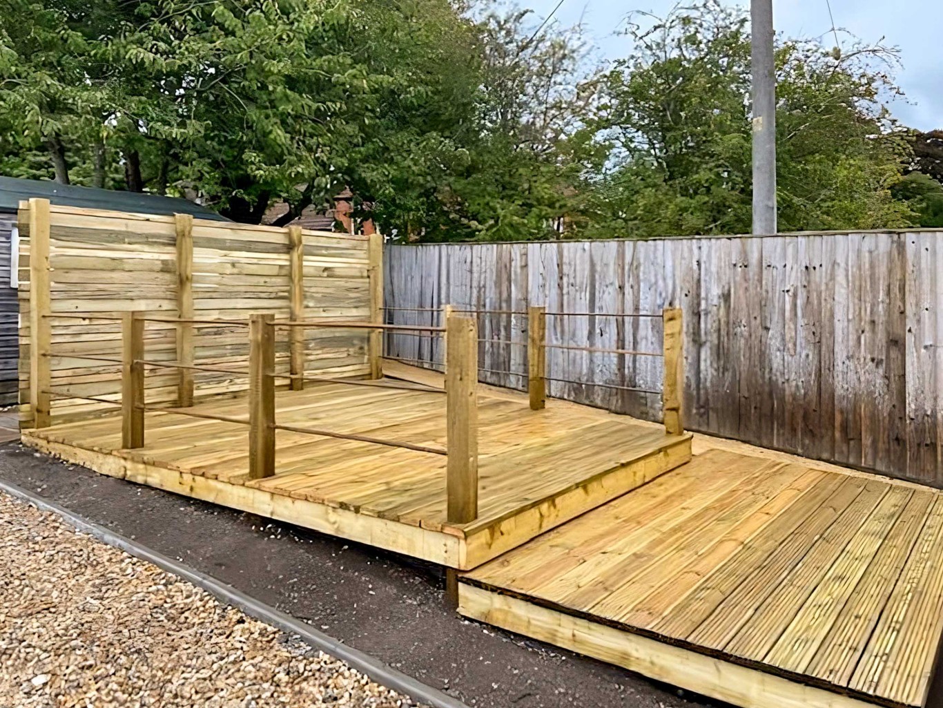 Large wooden decking project completed at top of garden with two levels.