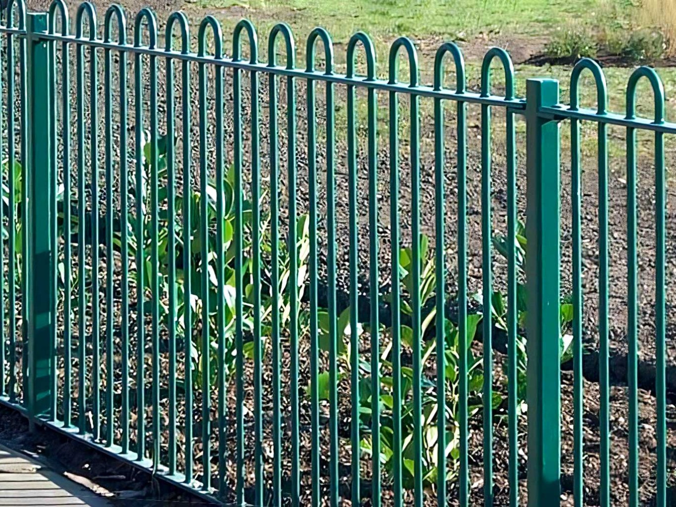 Green metal bow top fencing close up.