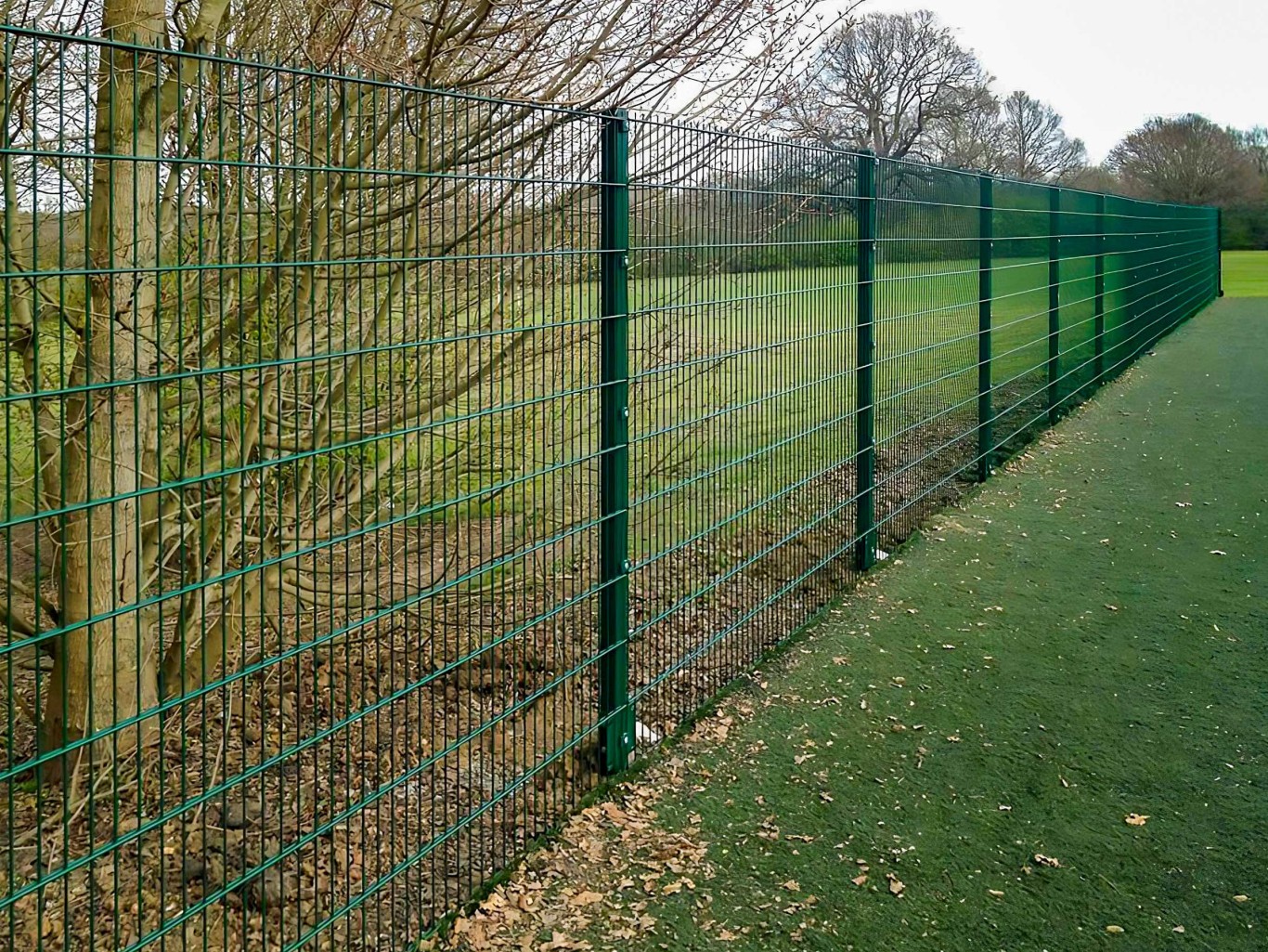 Green v mesh fencing around large fielded area.