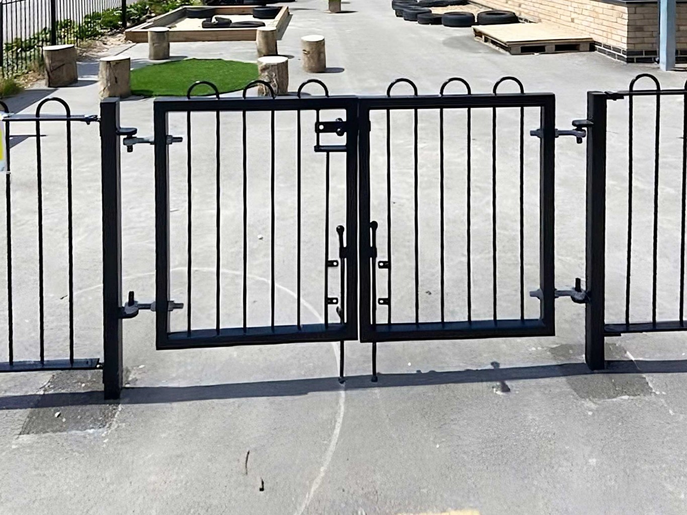 Black iron gates surrounding a school playground area.