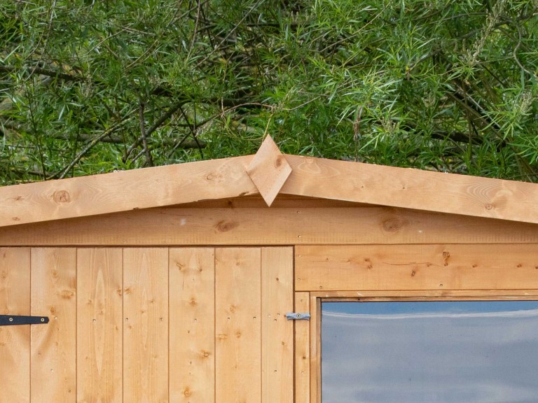 Close up of shed roof with wooden diamond shape in the middle.