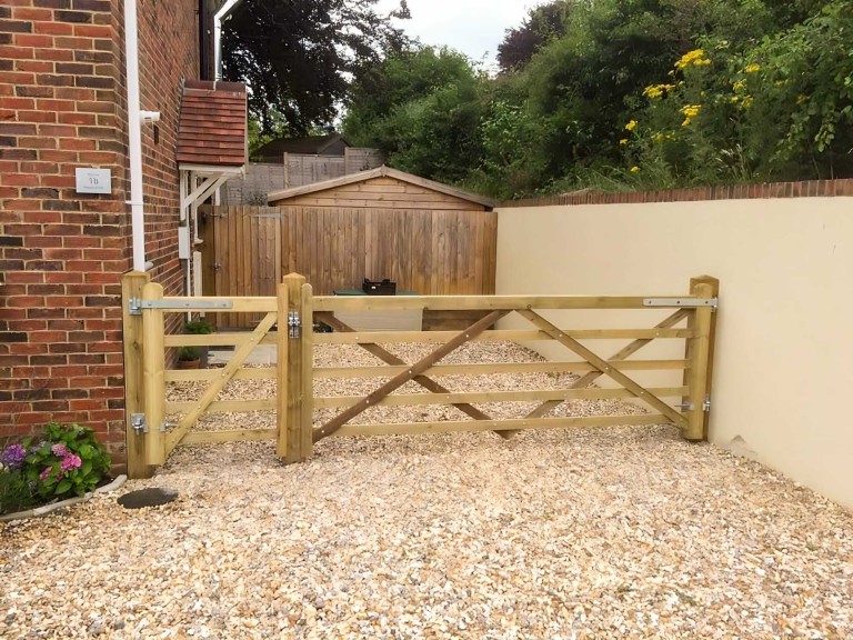 Completed wooden gate across a stoned driveway.