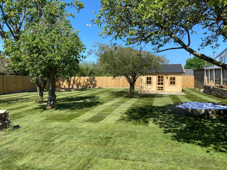 Large landscaping project with new grass, fencing and wooden shed.