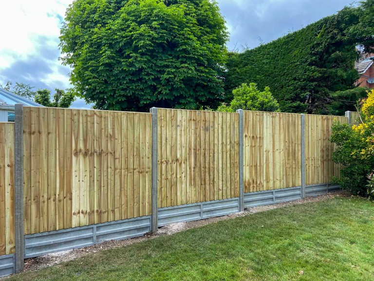 Closeboard fence with vertical boards and concrete posts.