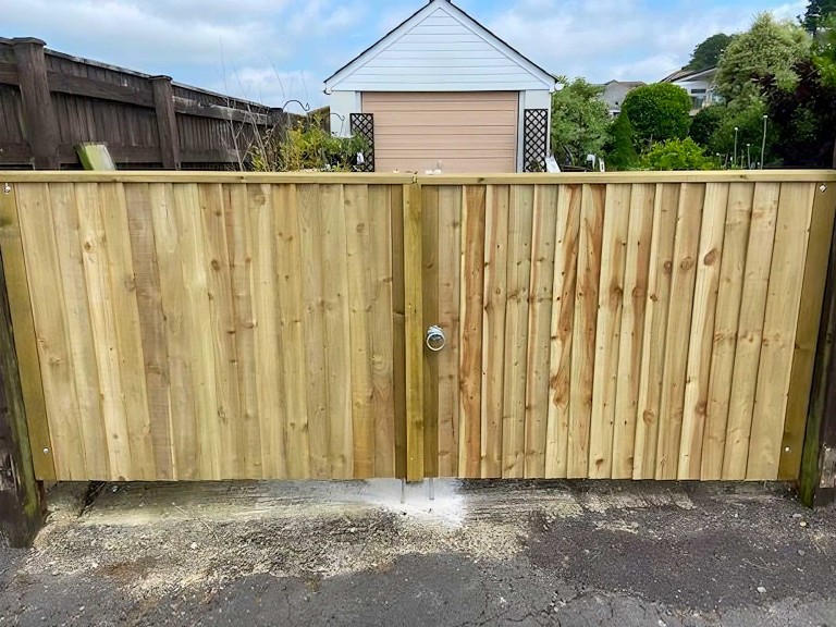 Pair of large closeboard gates made out of wood with a silver rounded handle.