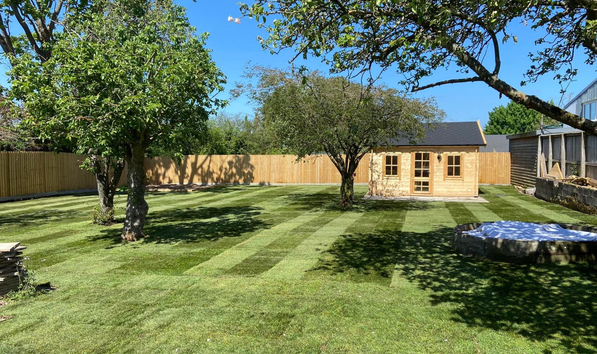 Large landscaping project with new grass, fencing and wooden shed.