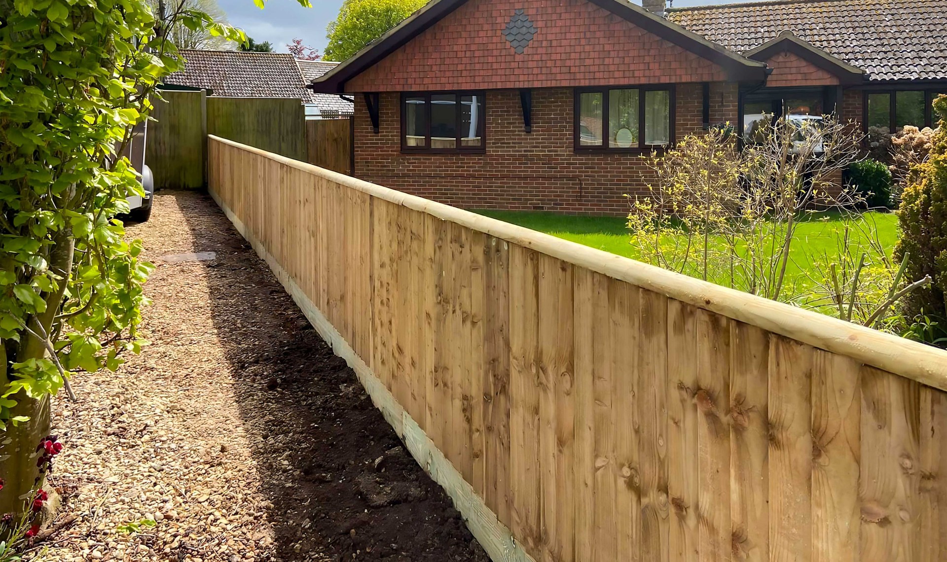 Small closeboard fence along the side of a garden with property in background.