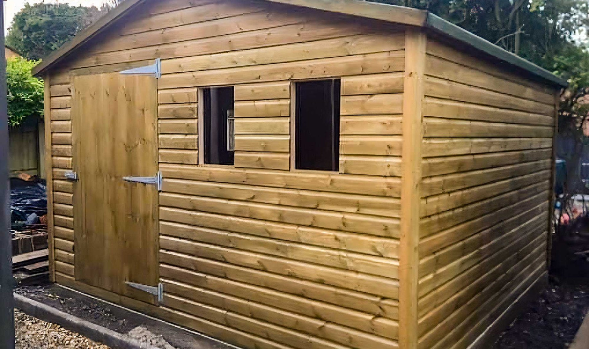 Large workshop shed in garden with two front windows.