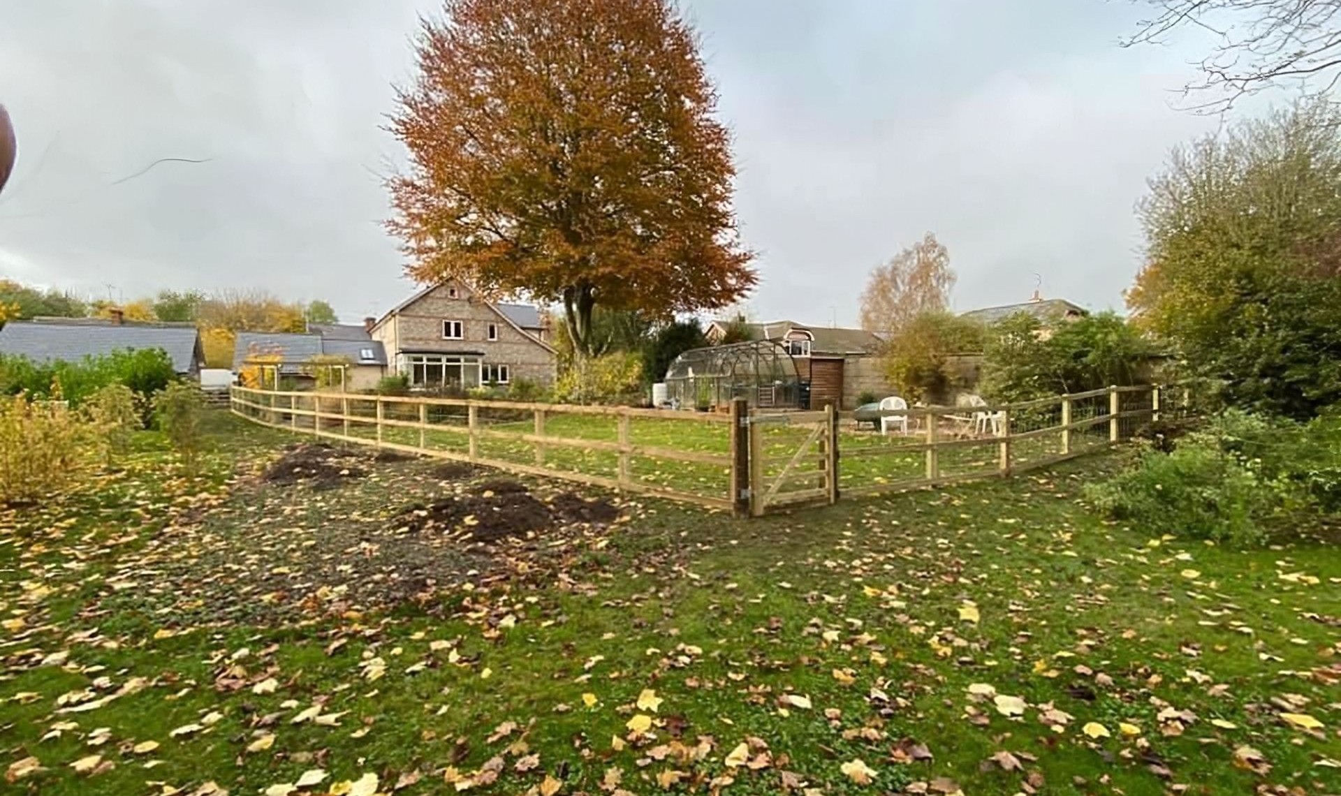 Completed long post and rail fence with wire netting from distance.