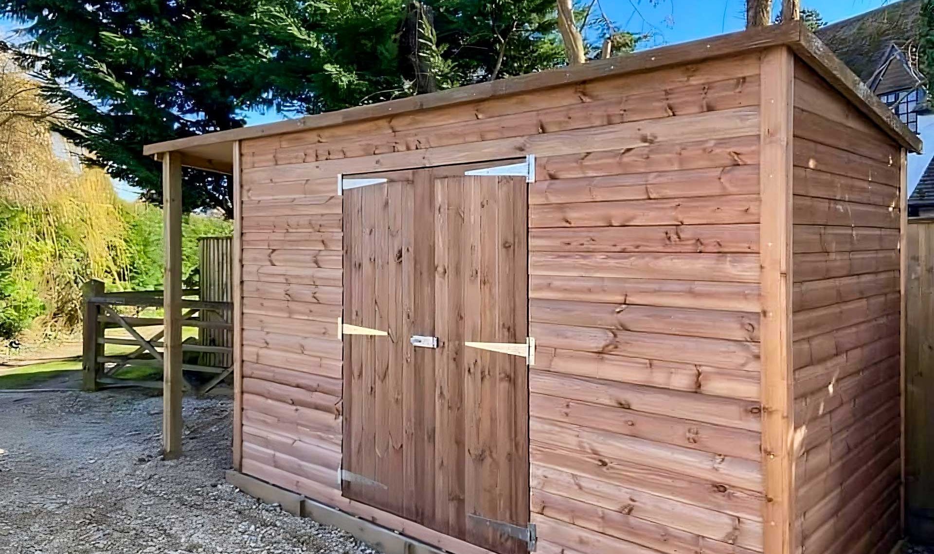 Large timber shed with double doors and shelter on the side.