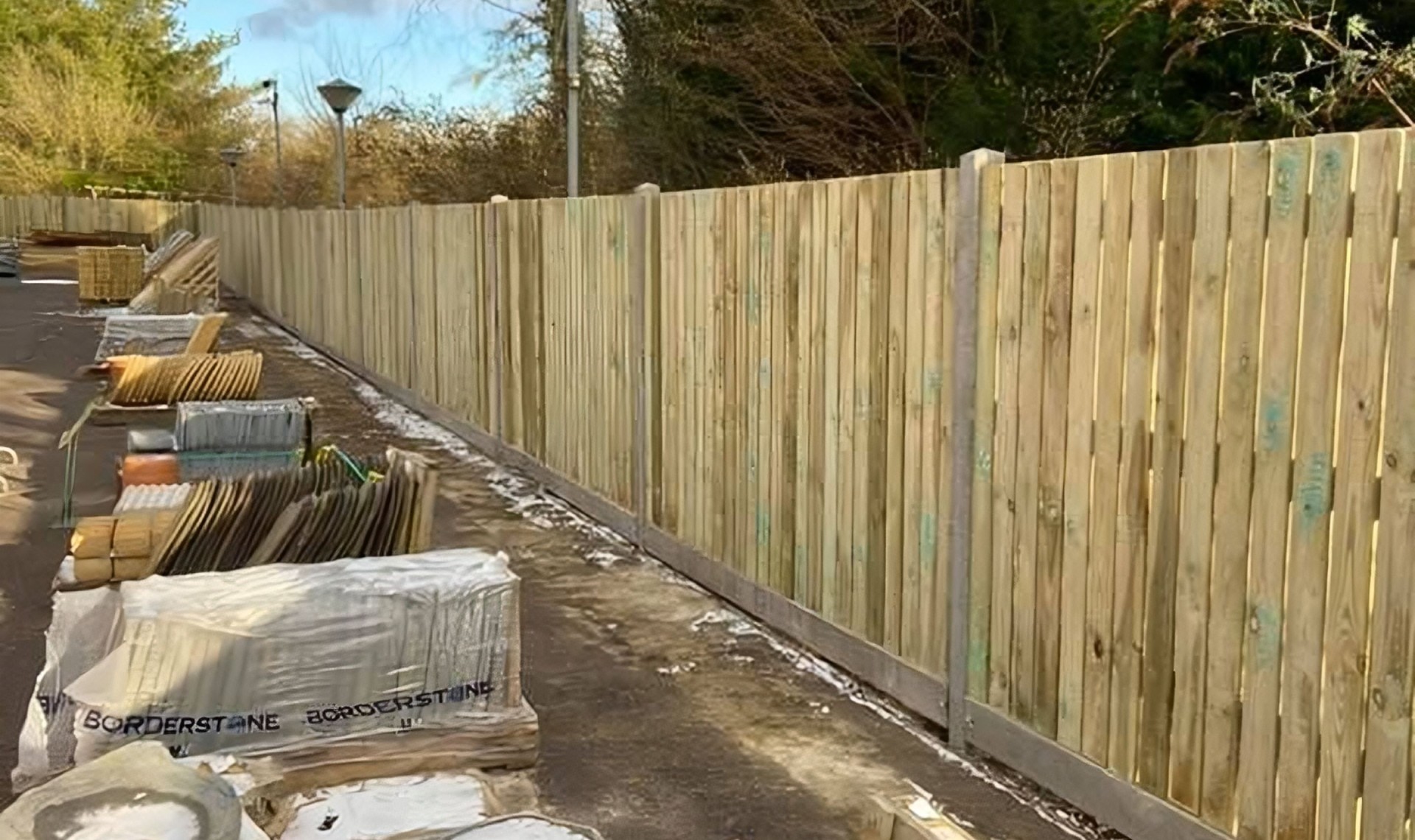 Close up of completed fence looking down the line with building materials.