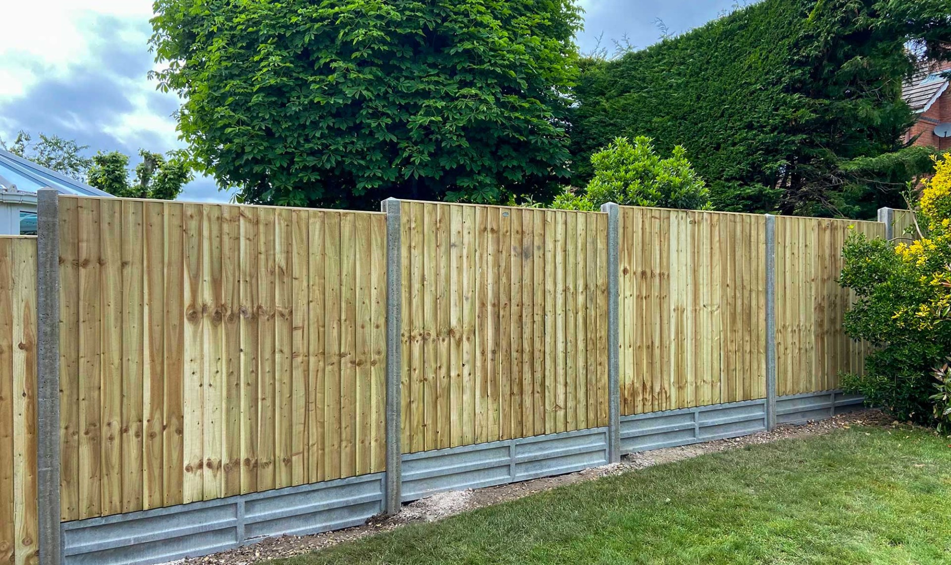 Closeboard fence with vertical boards and concrete posts.