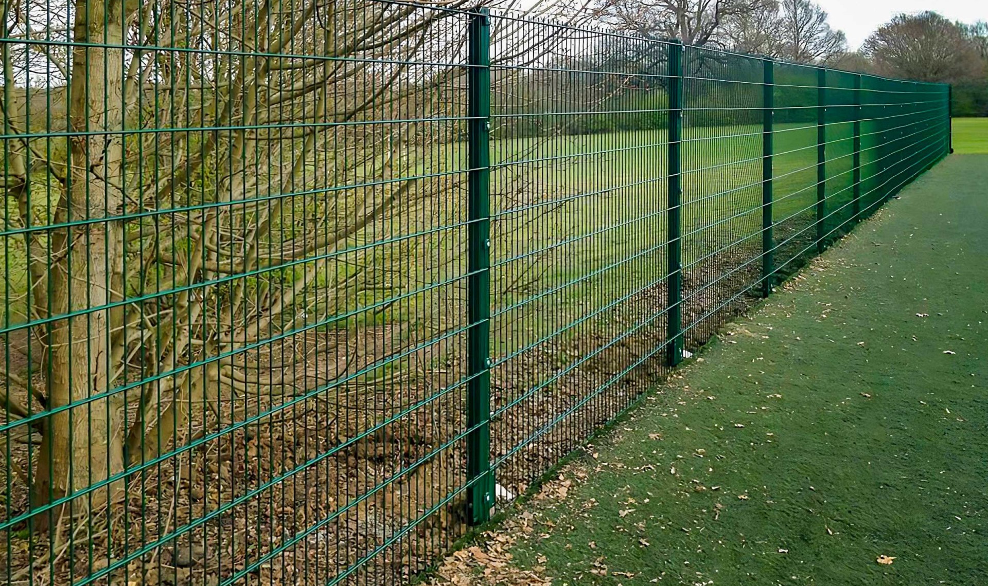 Green v mesh fencing around large fielded area.