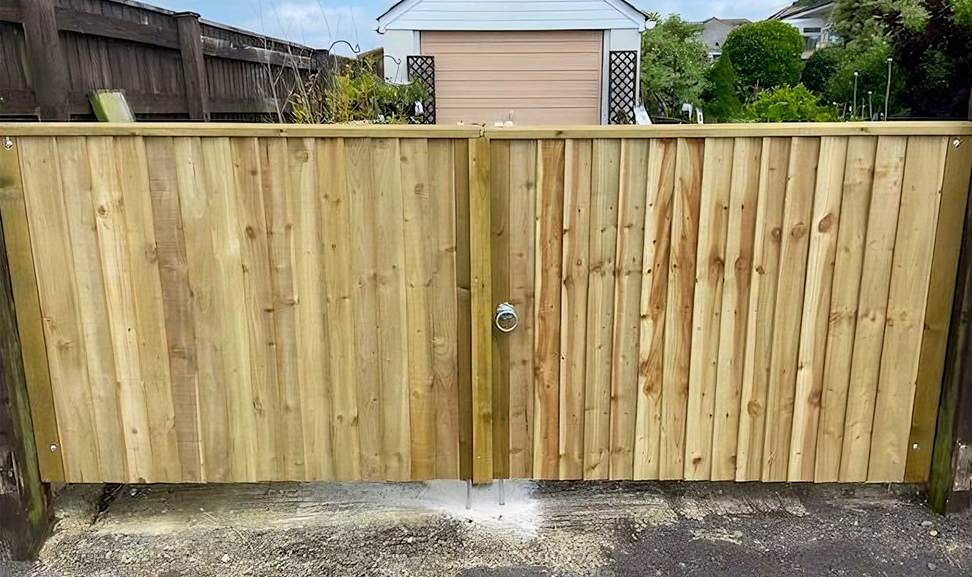Pair of large closeboard gates made out of wood with a silver rounded handle.