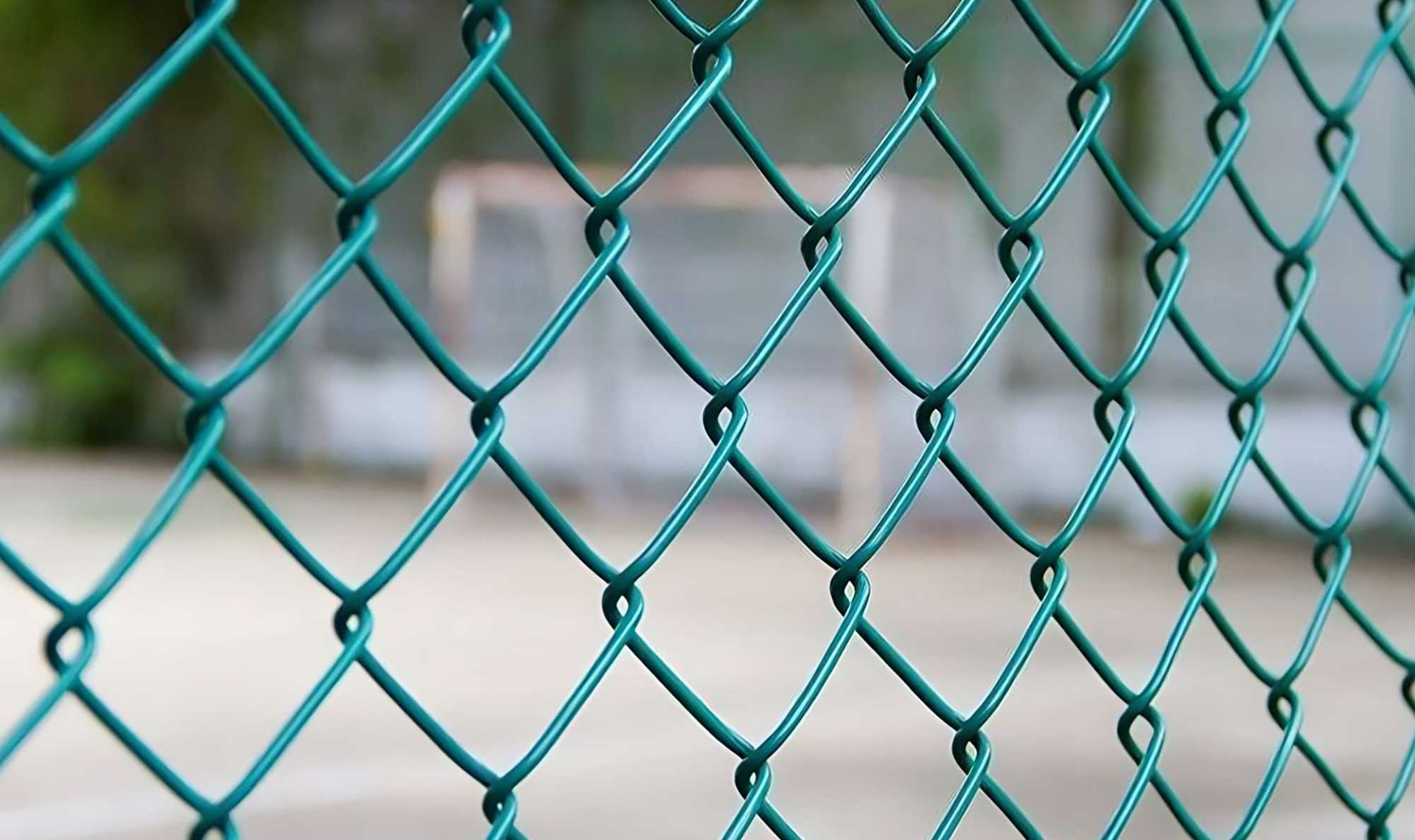 Close up of green chainlink fence with soft focus playground in background.